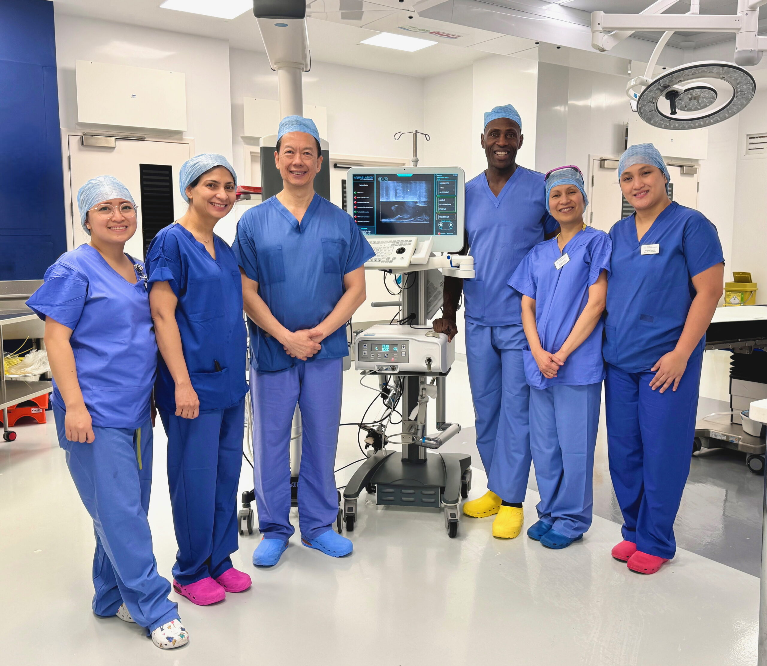 Group photo of HJE consultant and theatre team standing next to Aquablation equipment.