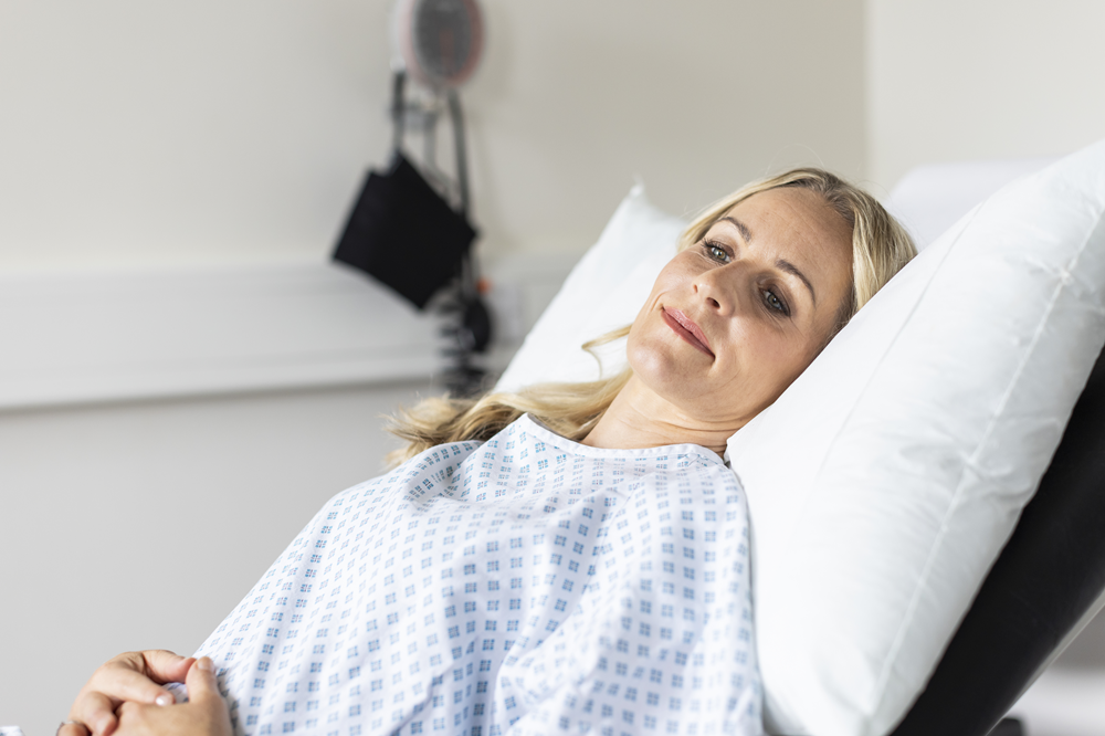 A woman lying on a hospital bed about to see a private urogynaecologist