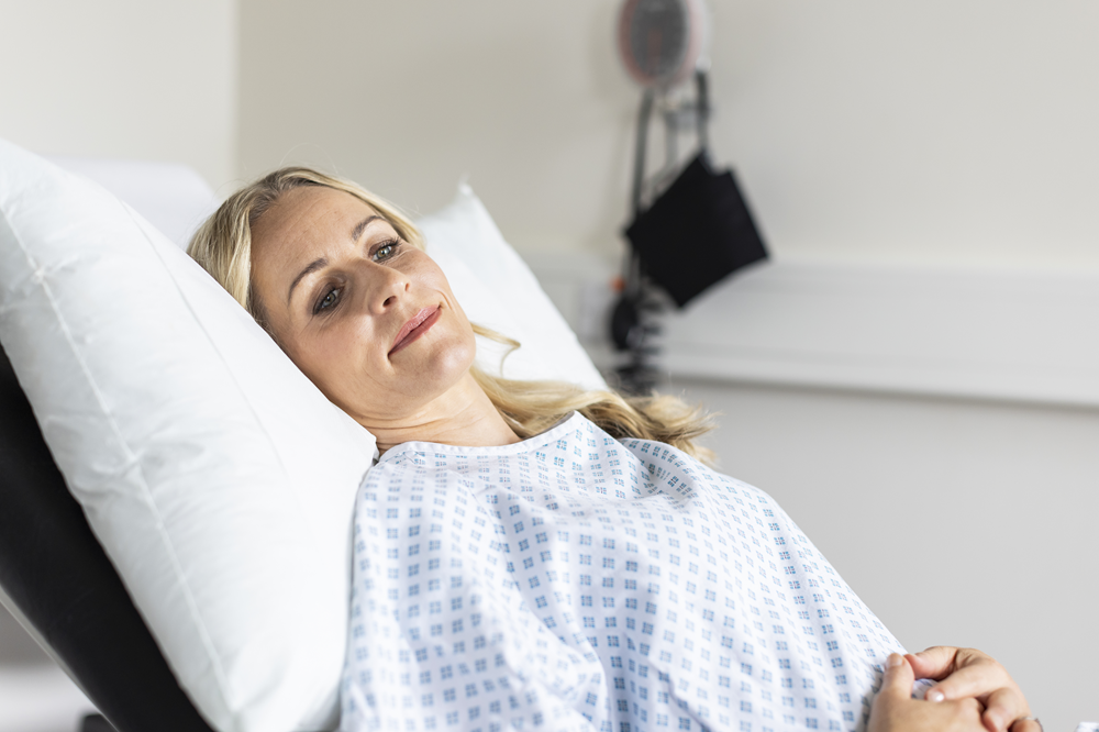 A woman lying on a hospital bed about to see a private urogynaecologist